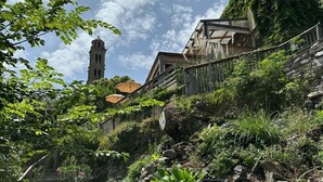 Ein Garten mit Steintreppen, die einen Hügel hinaufführen, einem Glockenturm und einem Gebäude mit einem geneigten Dach.