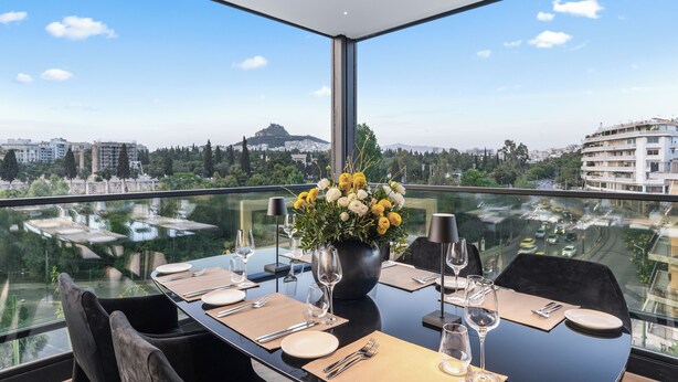 A dining table set for four with a view of a cityscape through a glass floor. - The Athenaeum Luxury Hotel (Athens)