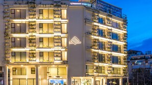 A multi-story hotel with balconies, a central entrance, and a logo on the facade. - The Athenaeum Luxury Hotel (Athens)