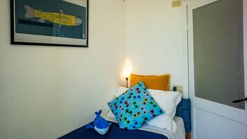 Quarto com cama, quadro na parede, abajur e janela com vista.