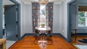 Un coin repas avec une table ronde, deux tabourets de bar et un lustre.