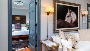 Une chambre d’hôtel avec un lit, un canapé, un portrait de cheval encadré et une petite table.