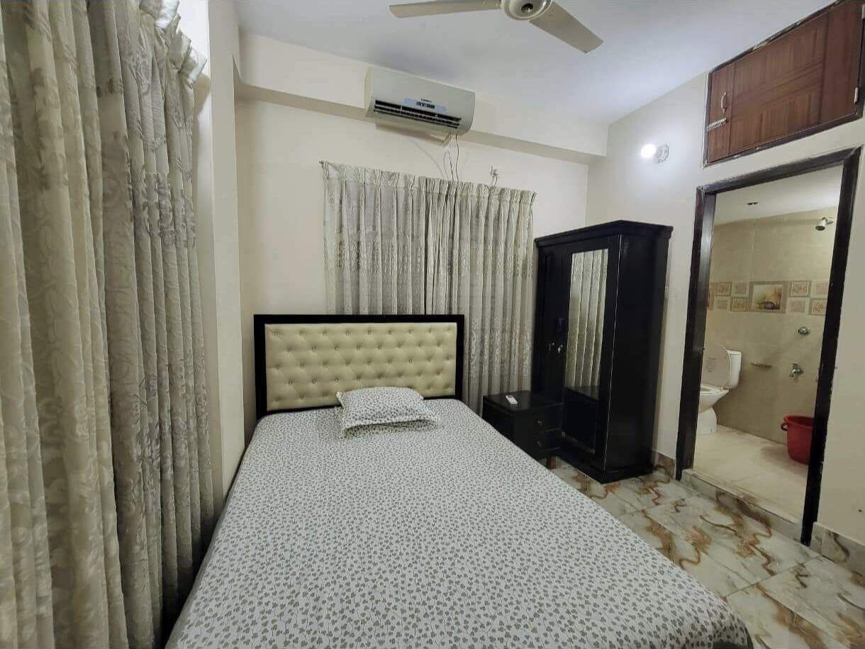 Un dormitorio con cama, armario, aire acondicionado y baño visible a través de una puerta abierta.