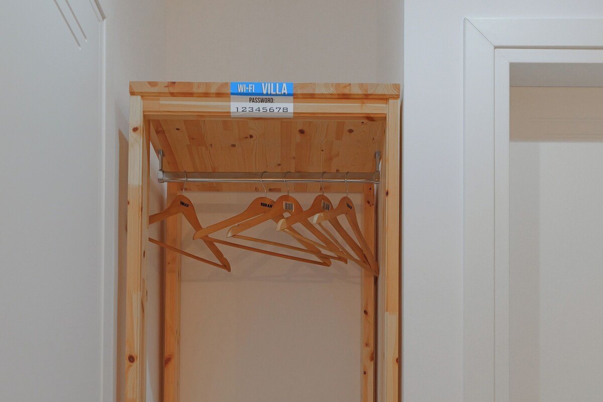 A compact room with a wooden wardrobe, a white intercom, and a small white refrigerator.