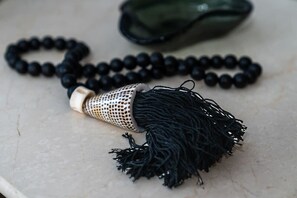 A black prayer bead necklace with a tassel, placed on a marble surface. - Expansive 1 Bedroom in Downtown Chs (Charleston)