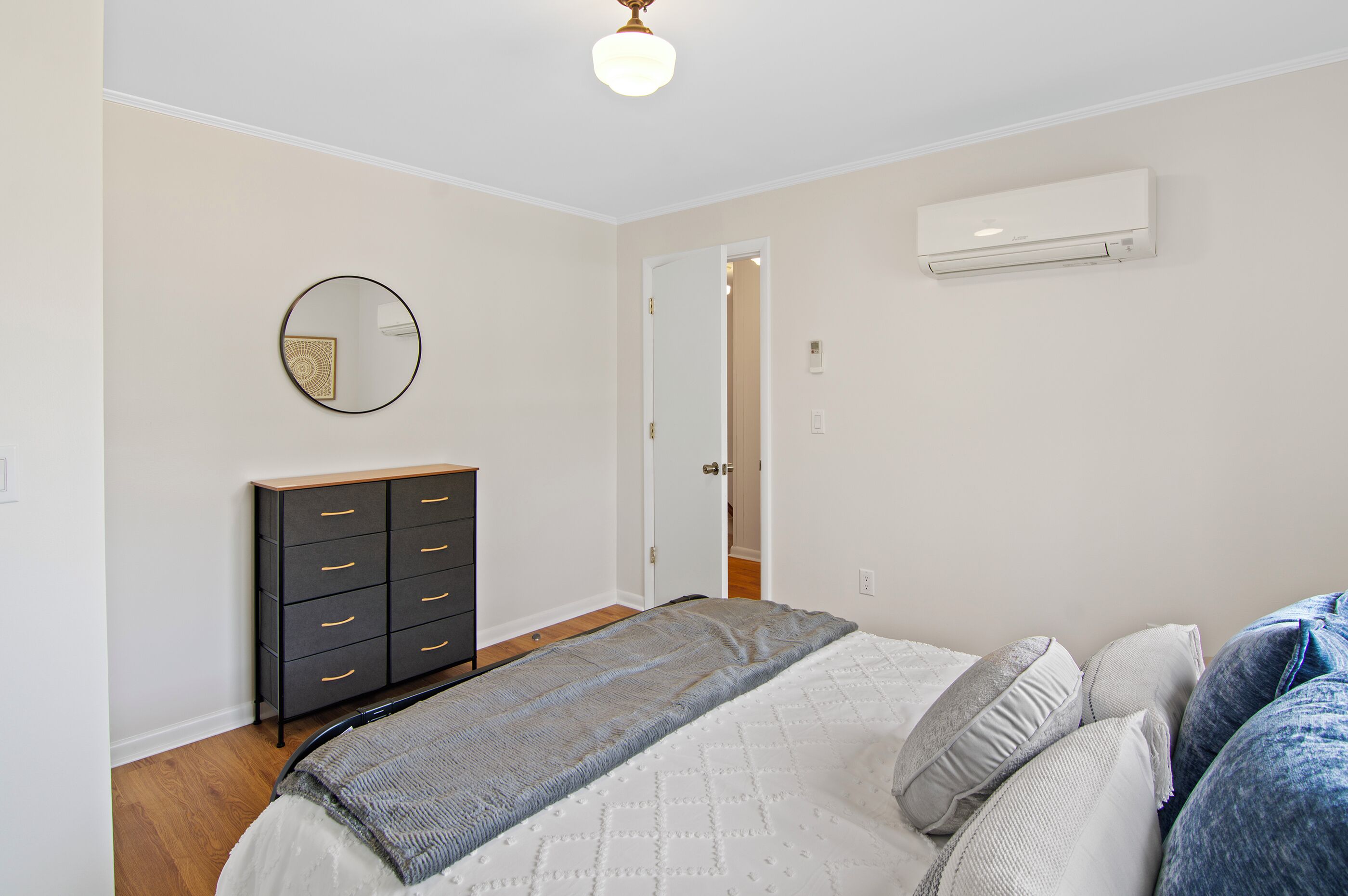 Ein Schlafzimmer mit Bett, Kommode, Spiegel und Klimaanlage.