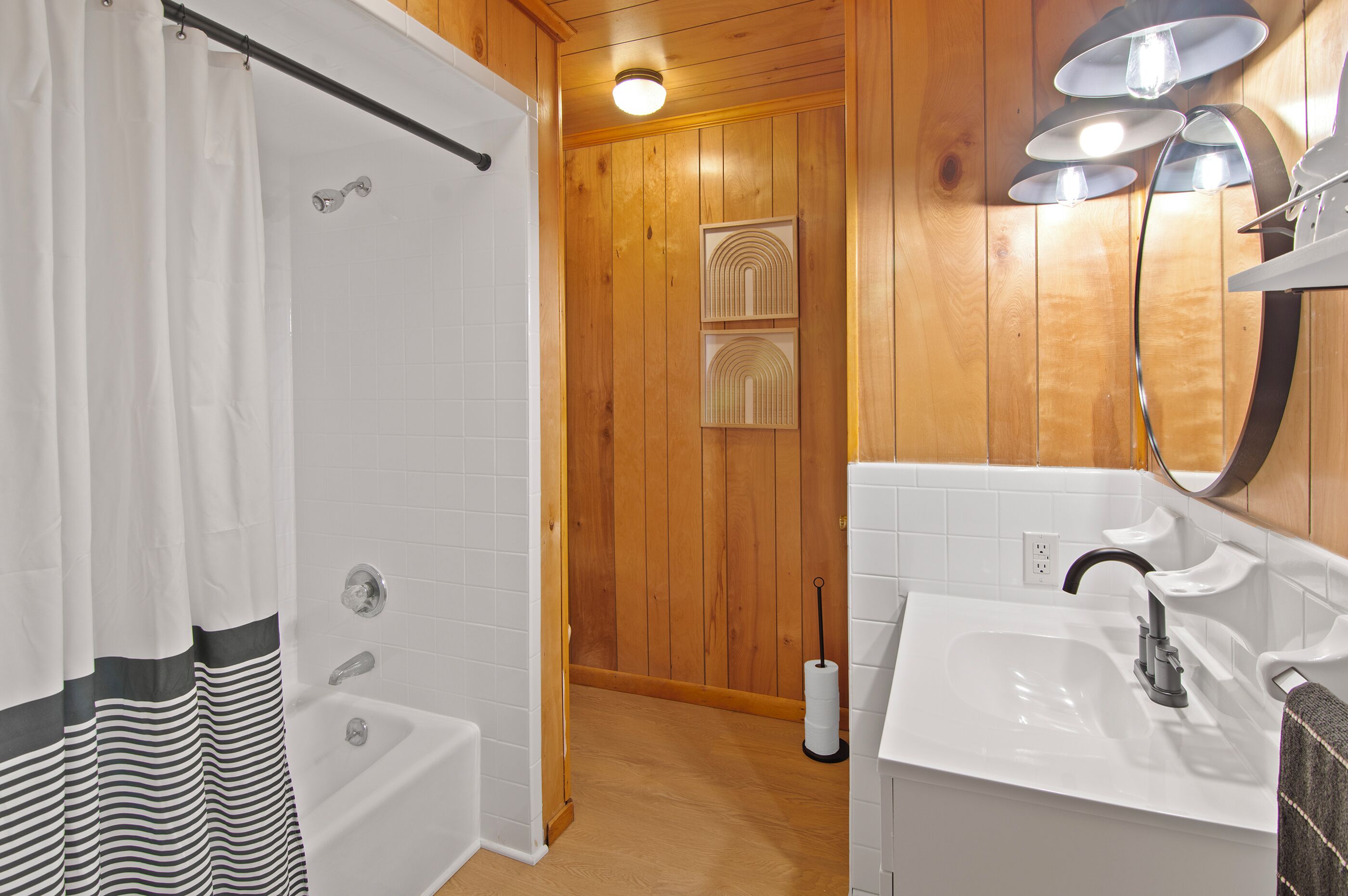 A bathroom with a bathtub, a sink, and wooden walls.