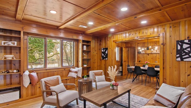 Un interior de madera con comedor, sofás y una mesa.