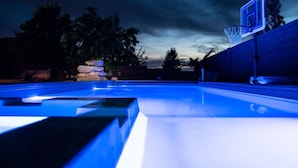An outdoor basketball court at dusk with a backboard and hoop, surrounded by trees and a stone wall. - House w/private pool & free access to Sand Hollow (Hurricane)