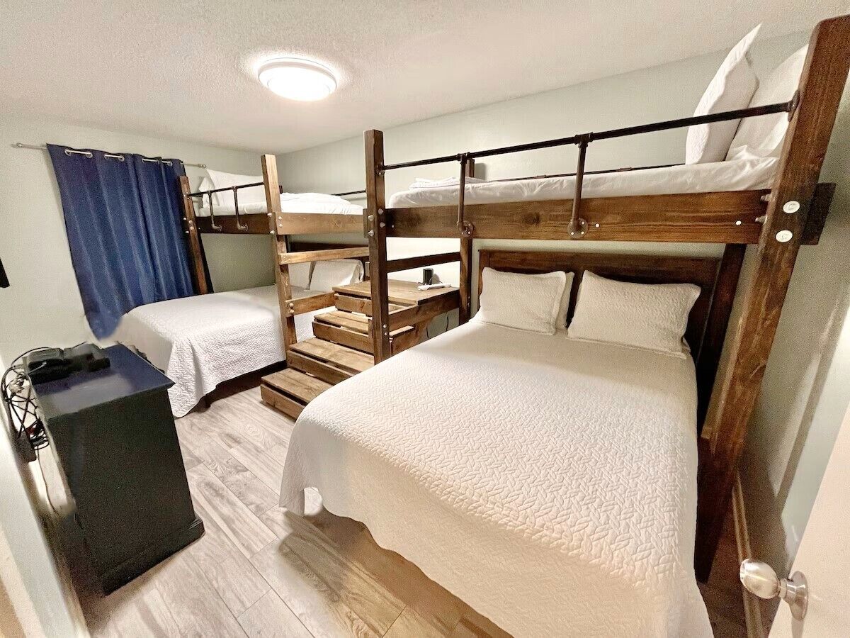 A bunk bed room with a desk and a blue curtain.