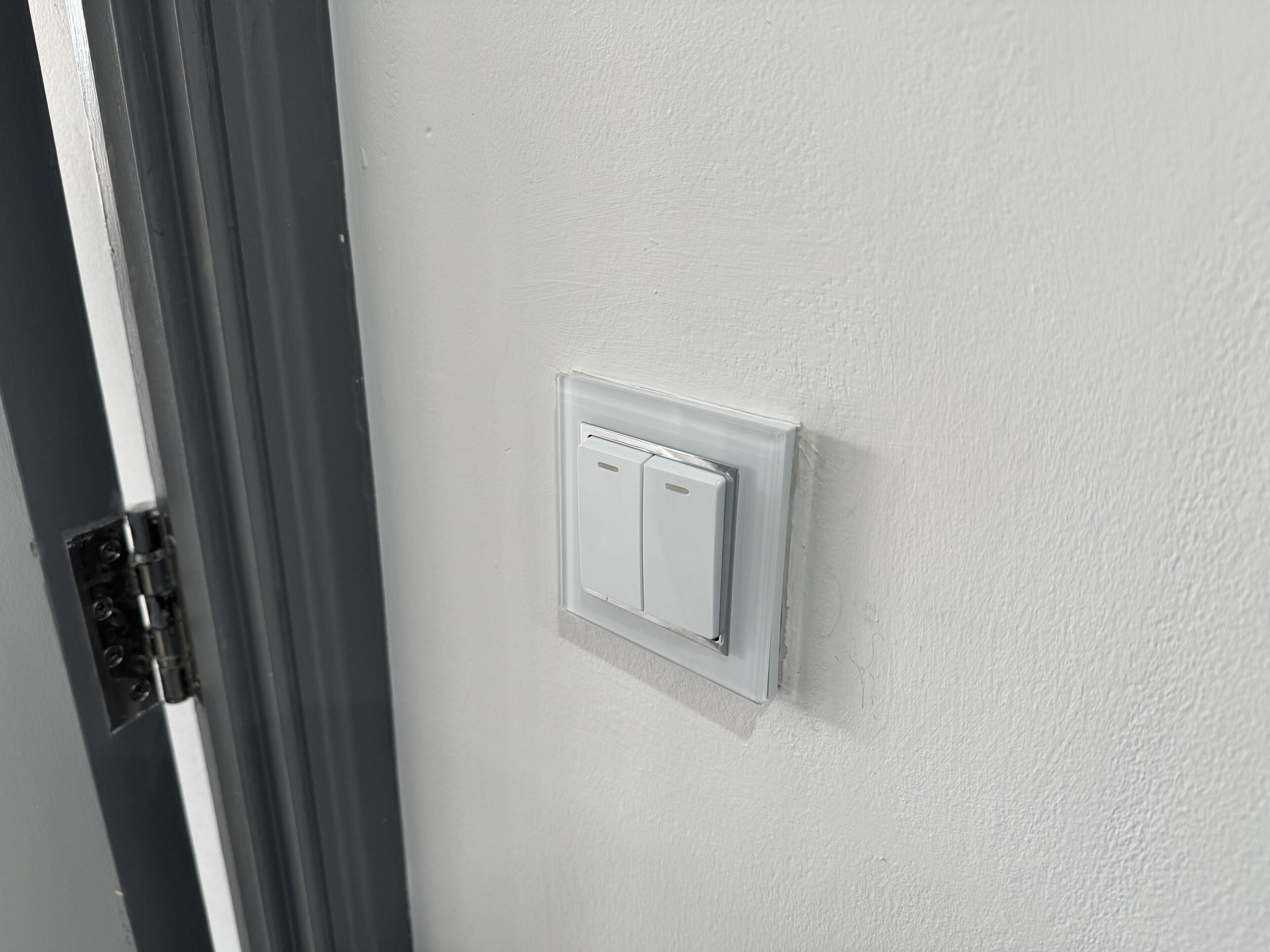 A white wall with a white electrical switch and a door frame.