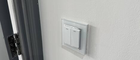 A white wall with a white electrical switch and a door frame.