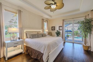Una camera da letto con un letto grande, un comodino con una lampada, un ventilatore a soffitto e vista all'esterno.