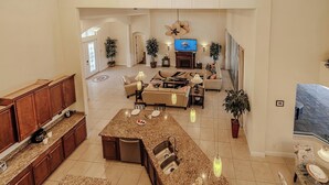 A spacious living area with a large kitchen island, a sofa set, and a TV. - Elegant 4-BR Tempur Pedic w/ Pvt Pool & Beach Access (Cape Coral)