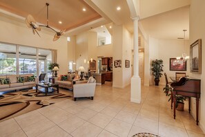 Relax in this spacious living area with a high ceiling, featuring a sofa set, coffee table, and piano.