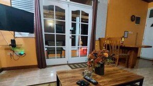 A living room with a wooden coffee table, a rug, and a TV mounted on the wall.