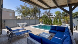 Un espace extérieur abrité avec une piscine, des chaises longues et un coin salon.