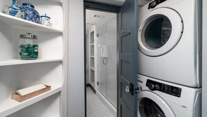 Une buanderie avec des machines à laver superposées et des étagères ornées d’objets décoratifs.