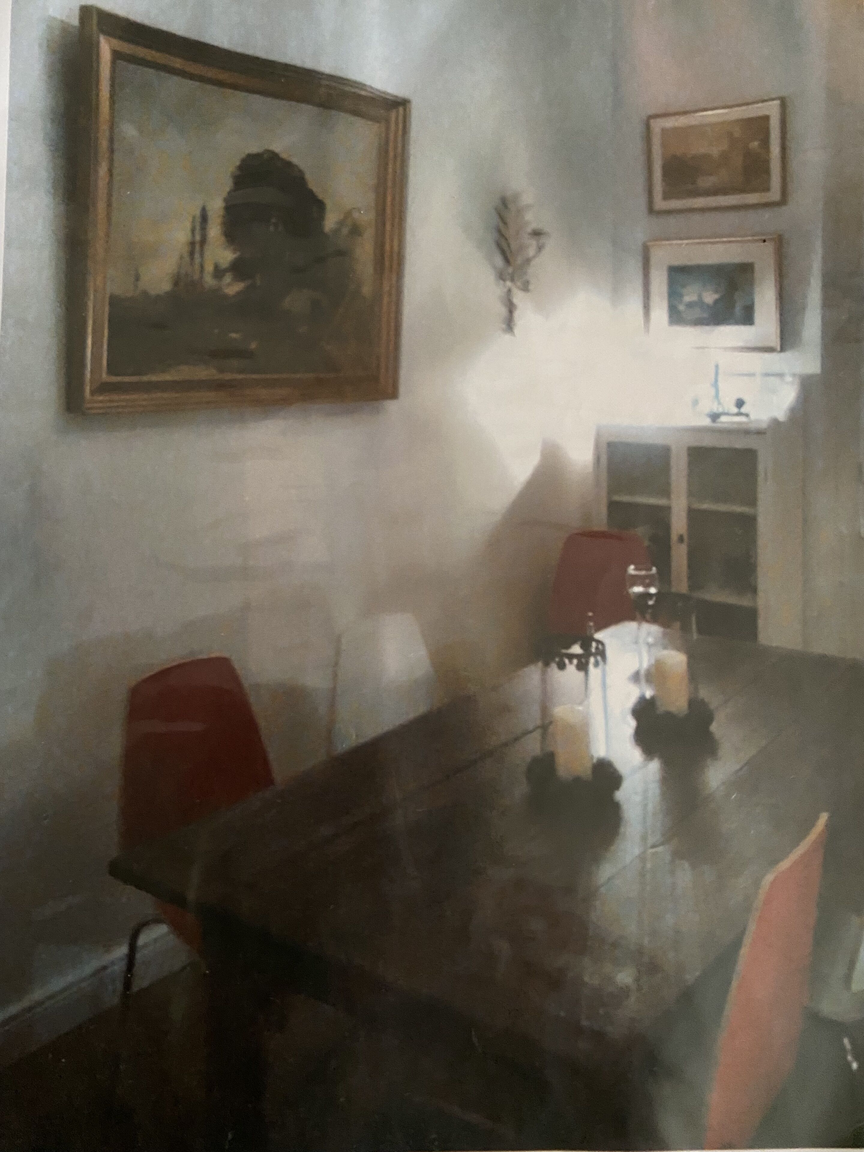 A dining area with a wooden table, red chairs, and a painting on the wall.