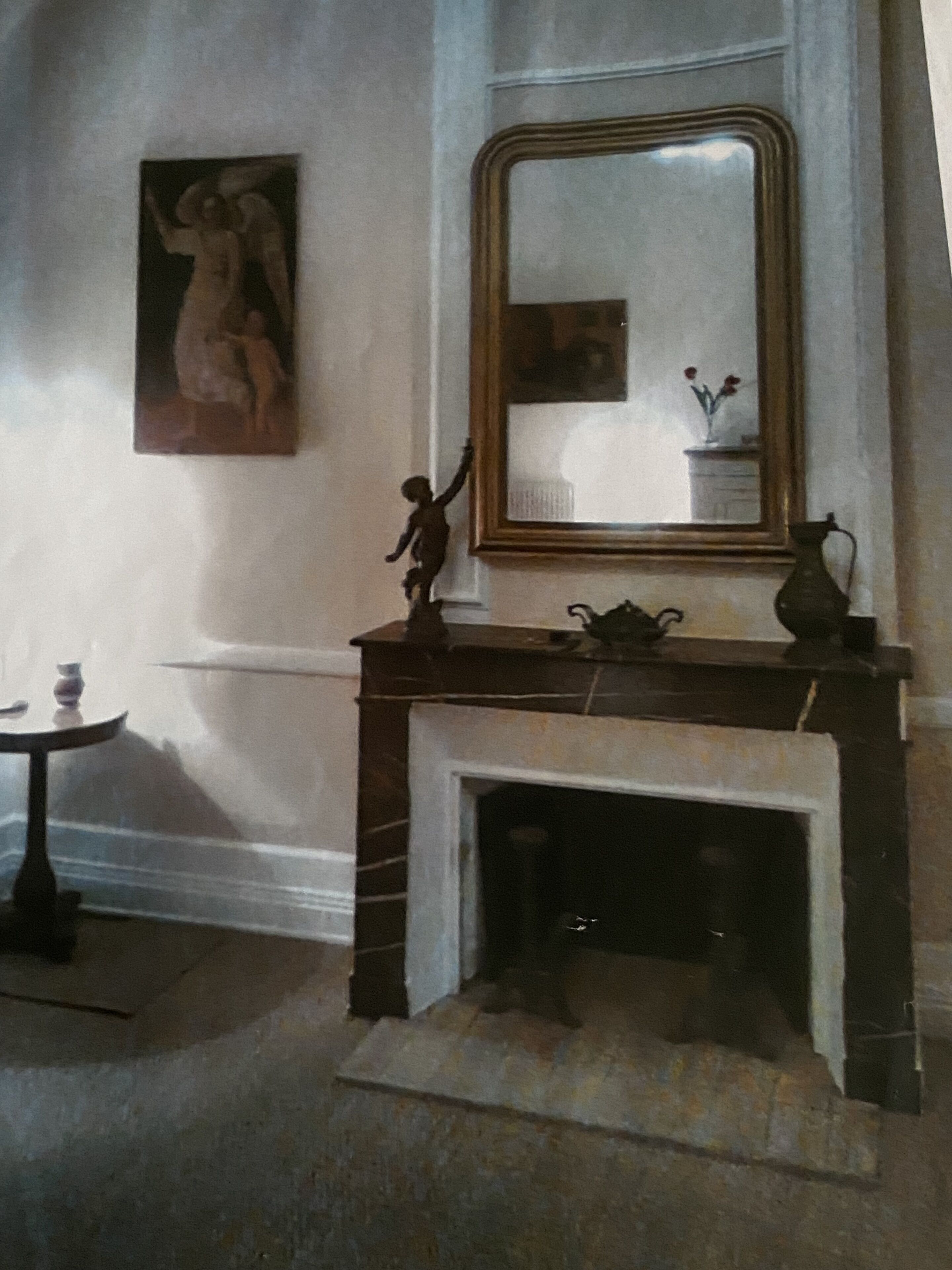 Een kamer met een open haard, een spiegel, een kleine tafel met een vaas en een schilderij aan de muur.