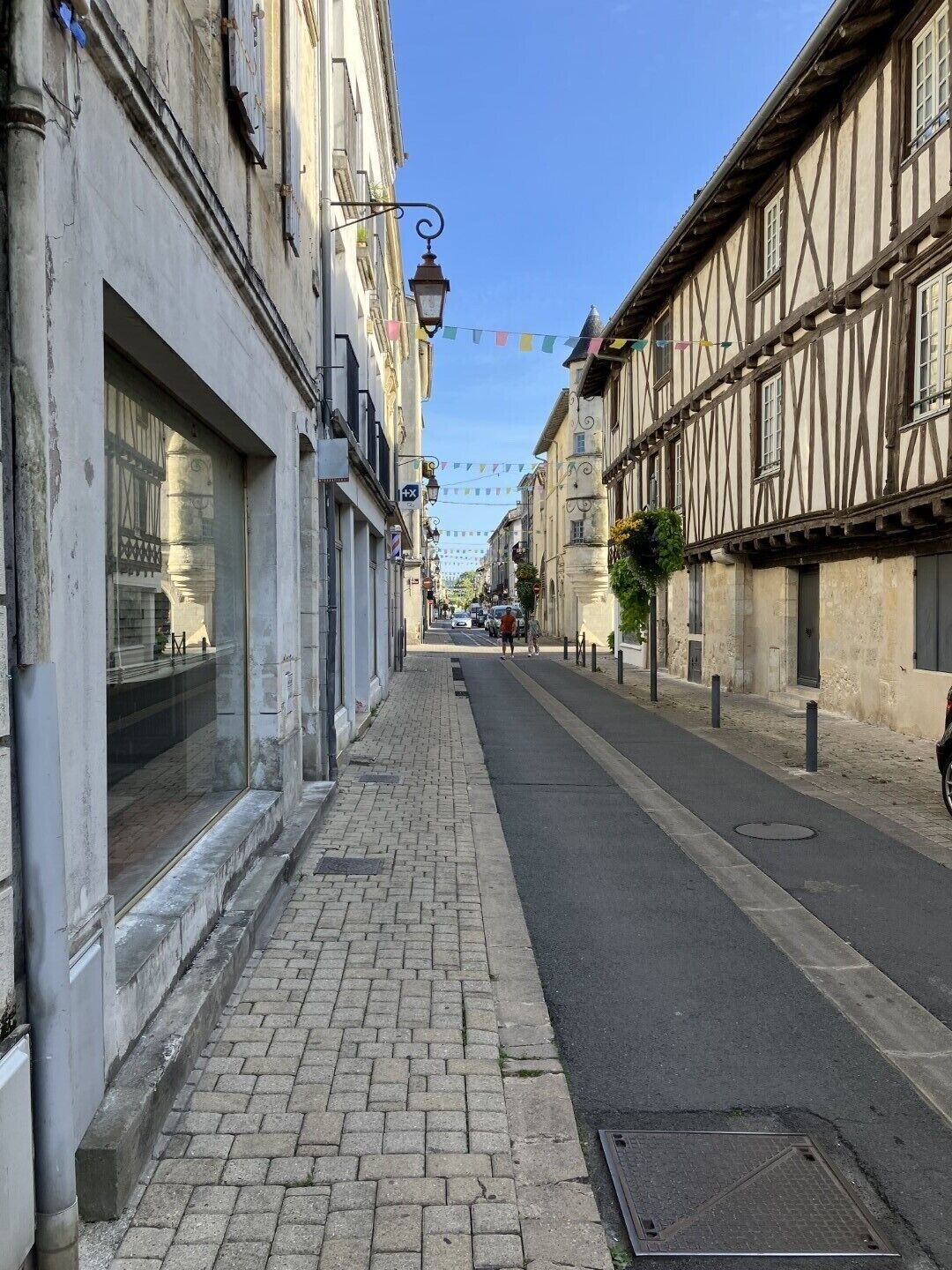 Une ruelle étroite pavée, bordée de bâtiments historiques à colombages et dotés de grandes fenêtres.