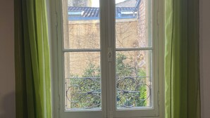 A room with a large window, green curtains, and a wicker basket on the floor.