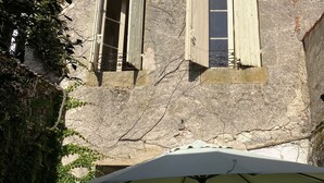 A building with two windows, one of which is open. There is a white umbrella in the foreground.