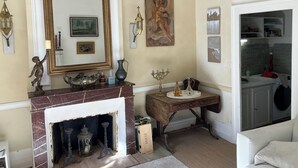 A living room with a fireplace, a large mirror, and a painting on the wall.
