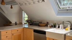 A modern kitchen with wooden cabinets, a dishwasher, and a skylight.