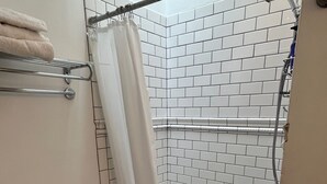 A bathroom with a toilet, a shower with a white curtain, and a bathtub.