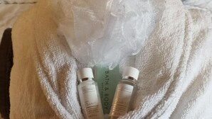 A white bathrobe with three bottles of bath and body products. - Glamping Cabin - Great for Hikers - Breakfast Inc! (Swanage)