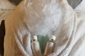 Un peignoir blanc accompagné de trois flacons de produits pour le bain et le corps.