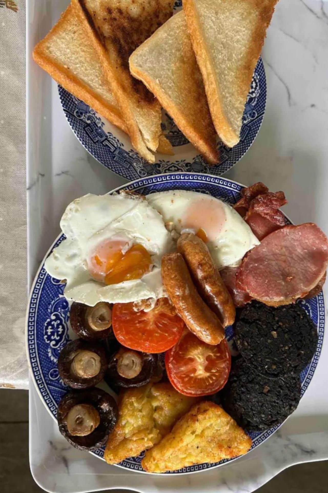 A plate with toast, eggs, sausages, tomatoes, mushrooms, and black pudding.