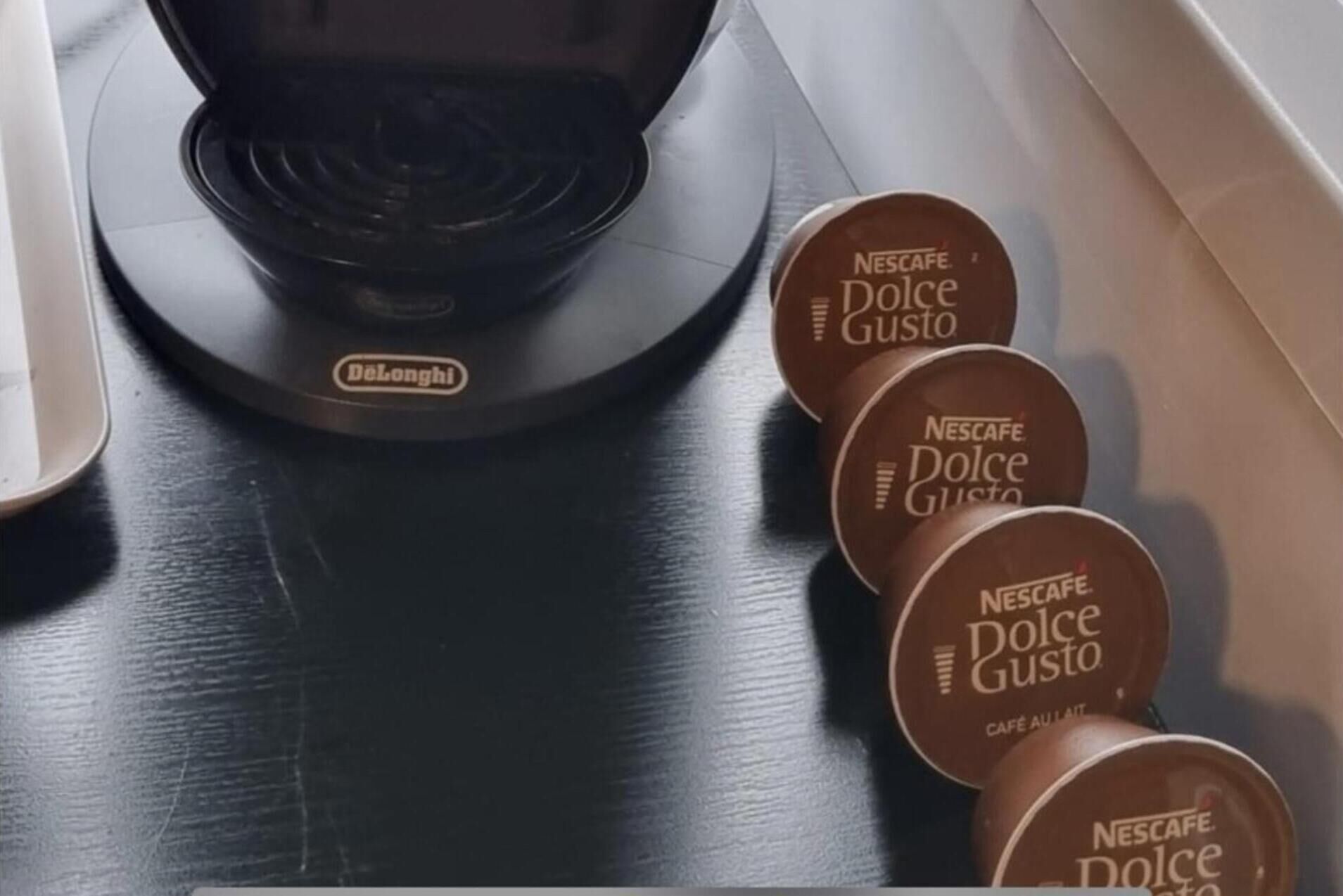 Eine Nescafe Dolce Gusto Kaffeemaschine und mehrere Nescafe Dolce Gusto Kaffeekapseln.