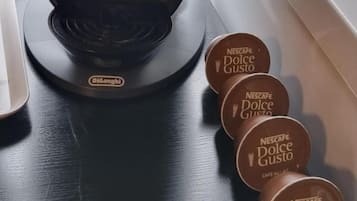 Eine Nescafe Dolce Gusto Kaffeemaschine und mehrere Nescafe Dolce Gusto Kaffeekapseln.
