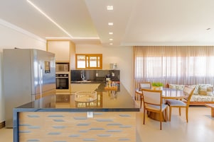 Una cocina moderna con una isla central, electrodomésticos de acero inoxidable y un comedor con una mesa redonda y sillas.
