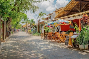 Una calle con mesas al aire libre, un restaurante llamado RESTAURANTE y un cartel de ENERGIA NATURAL.