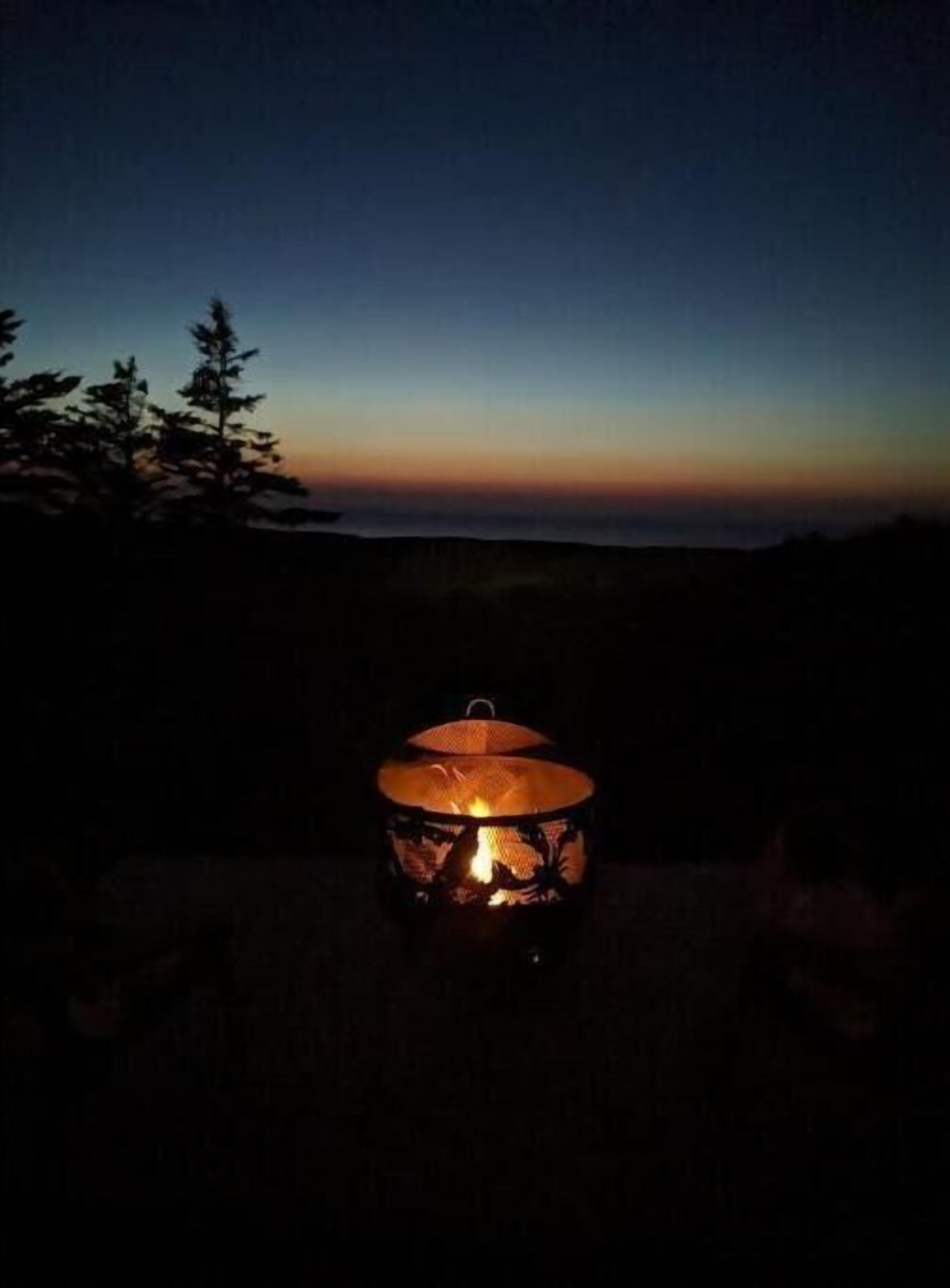 Um candeeiro com fogo no interior, colocado ao ar livre ao entardecer.
