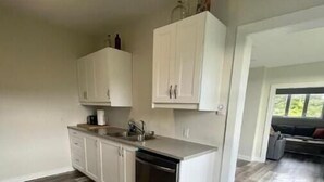 Una cucina moderna con mobili bianchi, lavastoviglie e un piano di lavoro.