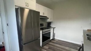 Una cucina con mobili bianchi, un frigorifero in acciaio inox e un forno integrato.