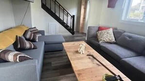 Un soggiorno moderno con un divano grigio, un tavolino in legno e una scala che conduce a un altro piano.