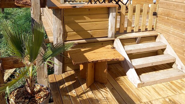 A wooden deck with a dining area, a small table, and a potted plant. - Chalet en Ferme Équestre au Plus Proche des Chevaux (Yèvres)