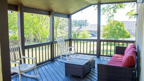 A covered porch with wicker furniture, including a rocking chair and a sofa with cushions. - Large colonial style house in the most sought after area - Ballantyne.  (Charlotte)