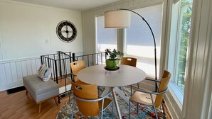 A dining area with a round table, chairs, a green plant, and a large window. - Table Rock Lakeview Home Retreat: Stunning Sunsets, Close to Eureka Springs (Holiday Island)