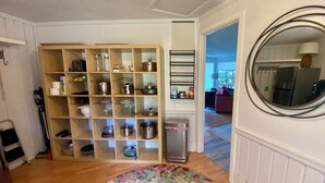 A kitchen with wooden shelves holding pots and pans, a trash can, and a round mirror on the wall. - Table Rock Lakeview Home Retreat: Stunning Sunsets, Close to Eureka Springs (Holiday Island)