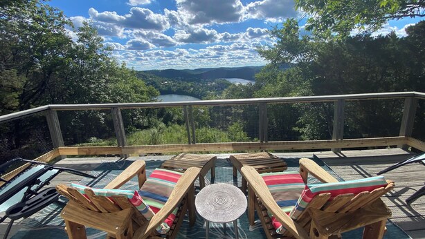 A deck with wooden chairs and a table, overlooking a scenic landscape with a lake and mountains. - Table Rock Lakeview Home Retreat: Stunning Sunsets, Close to Eureka Springs (Holiday Island)