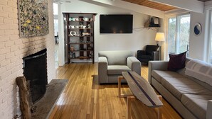 Una sala moderna con chimenea, una estantería, un televisor de pantalla plana y un sofá.