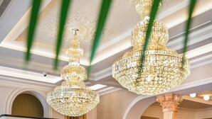 A grand lobby with a marble floor, a curved reception desk, and a large chandelier. - La Fe boutique Hotel Sarande (Sarandë)