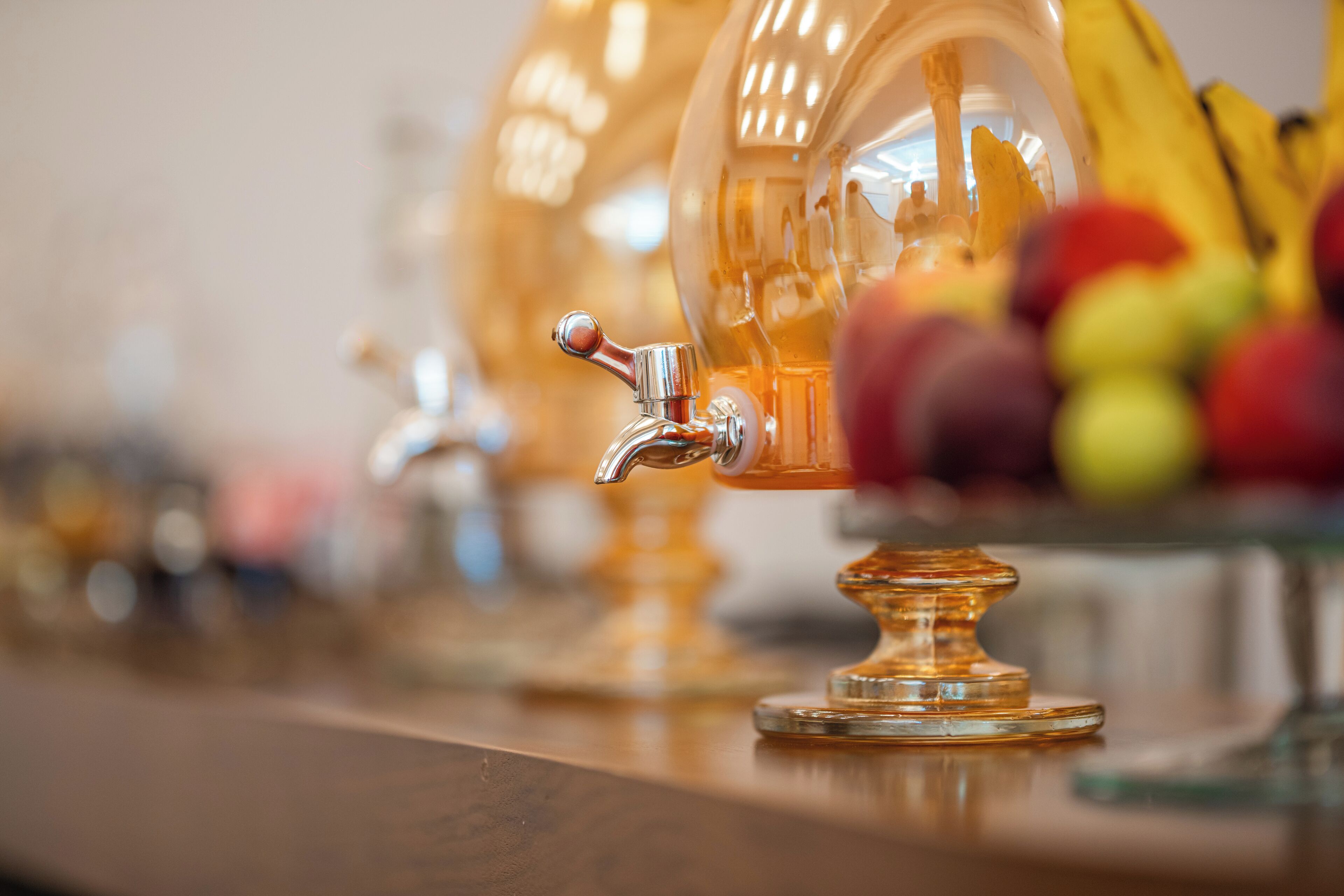 A row of clear glass dispensers with a metallic tap, likely for a beverage service.