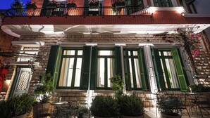 A building with a brick facade, green shutters, and outdoor seating with potted plants. - La Fe boutique Hotel Sarande (Sarandë)